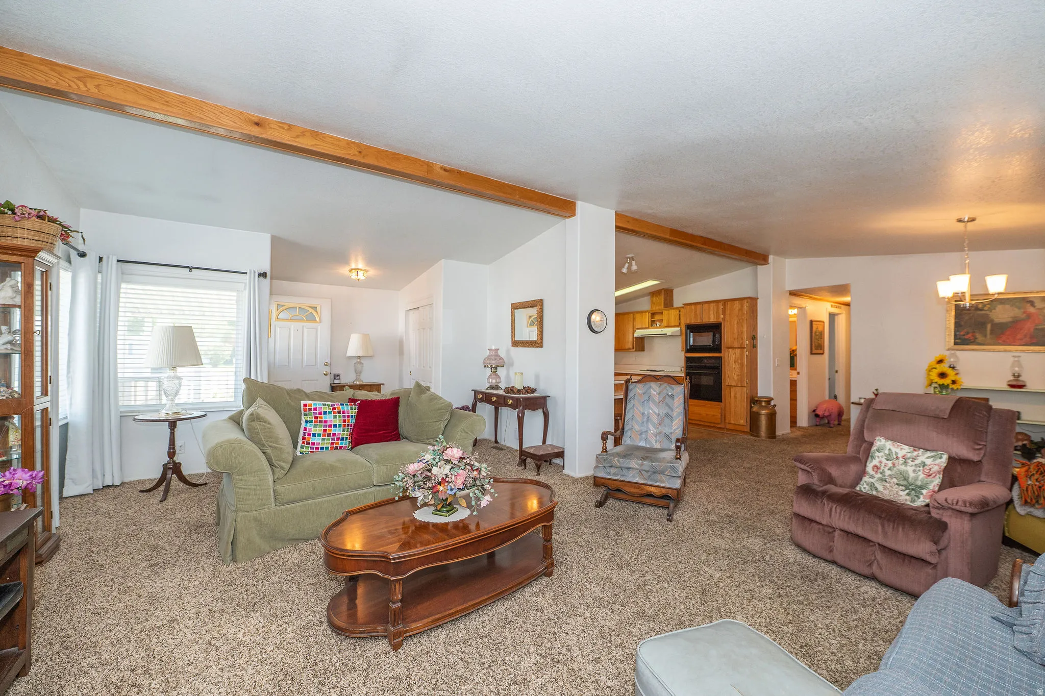 Open-concept living area with exposed beam accents, recessed lighting, and a front entry door with decorative glass