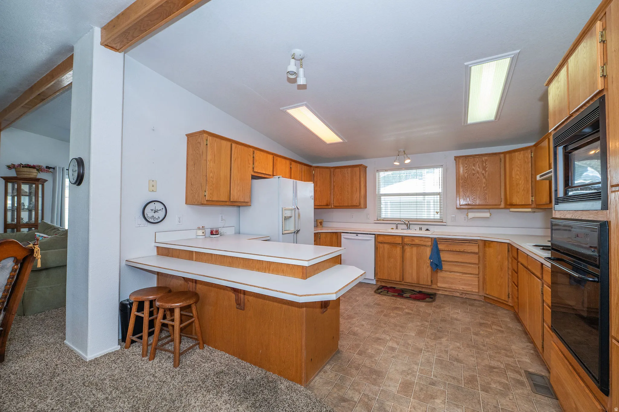 Expansive kitchen featuring light wood cabinetry, white countertops, built-in wall oven and microwave, and track lighting