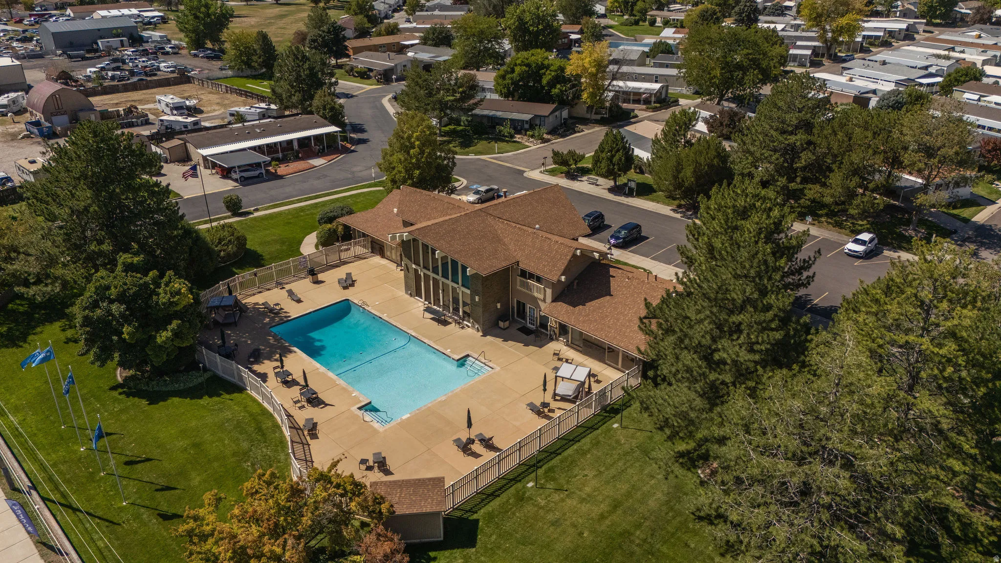 Expansive outdoor swimming pool with surrounding hardscaping, a privacy fence, and mature trees