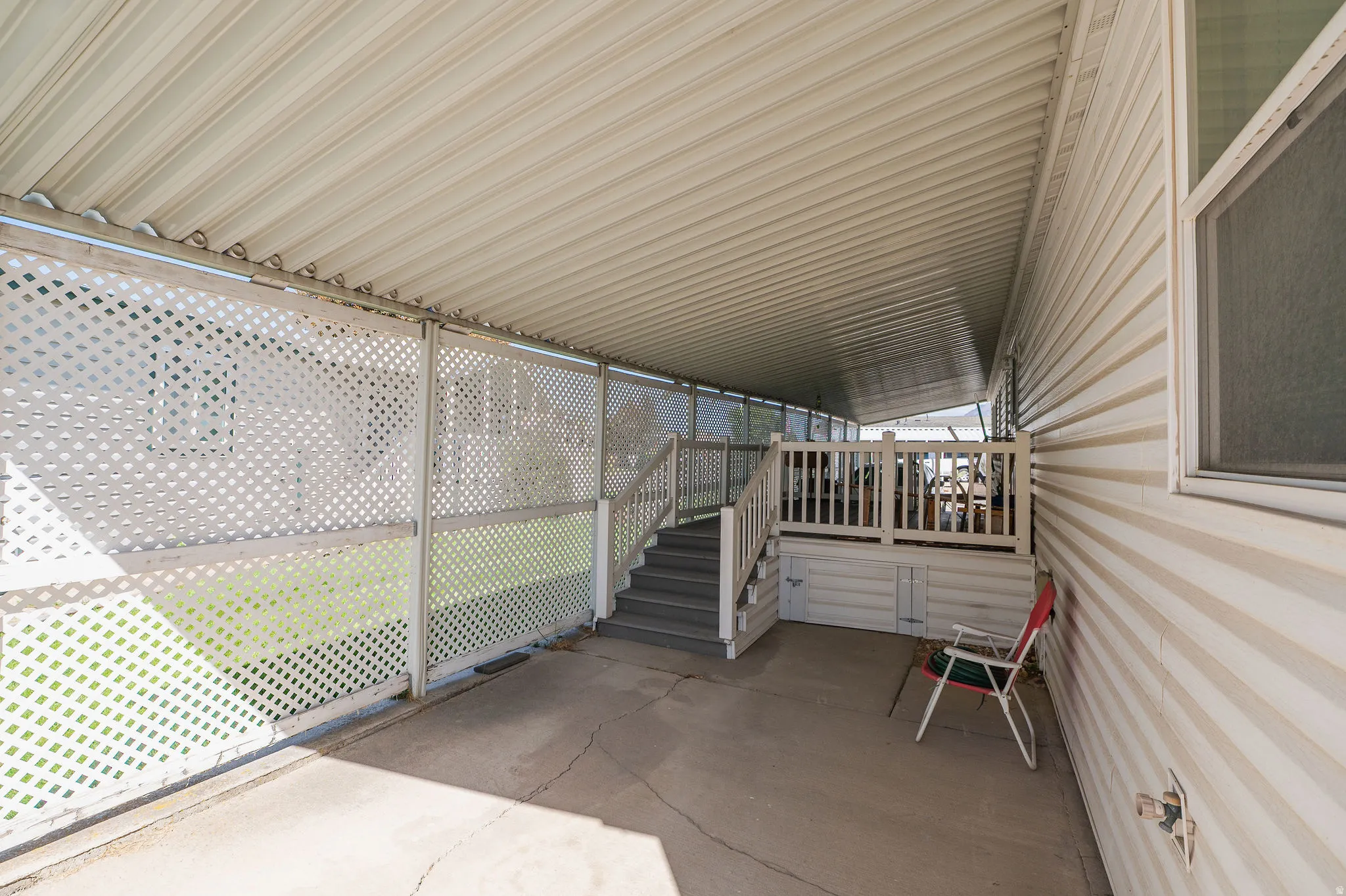 Expansive covered patio featuring a concrete floor, lattice fencing, and exterior vinyl siding