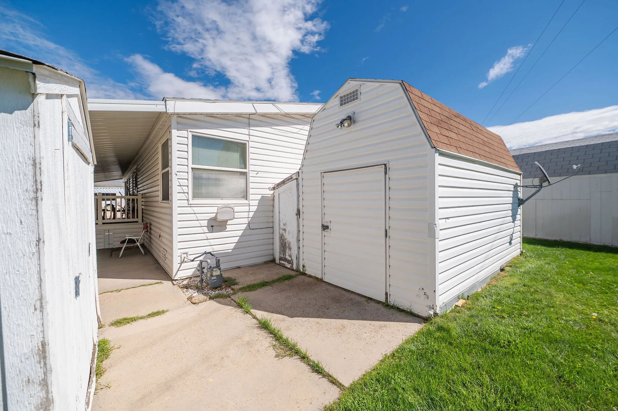 Exterior featuring white horizontal siding, a detached storage shed with a gambrel roof, and a covered patio area