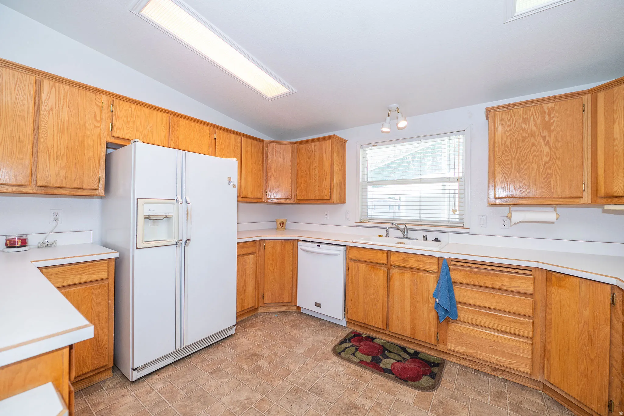 Kitchen featuring wood cabinetry, white countertops, built-in dishwasher, and a double-door refrigerator