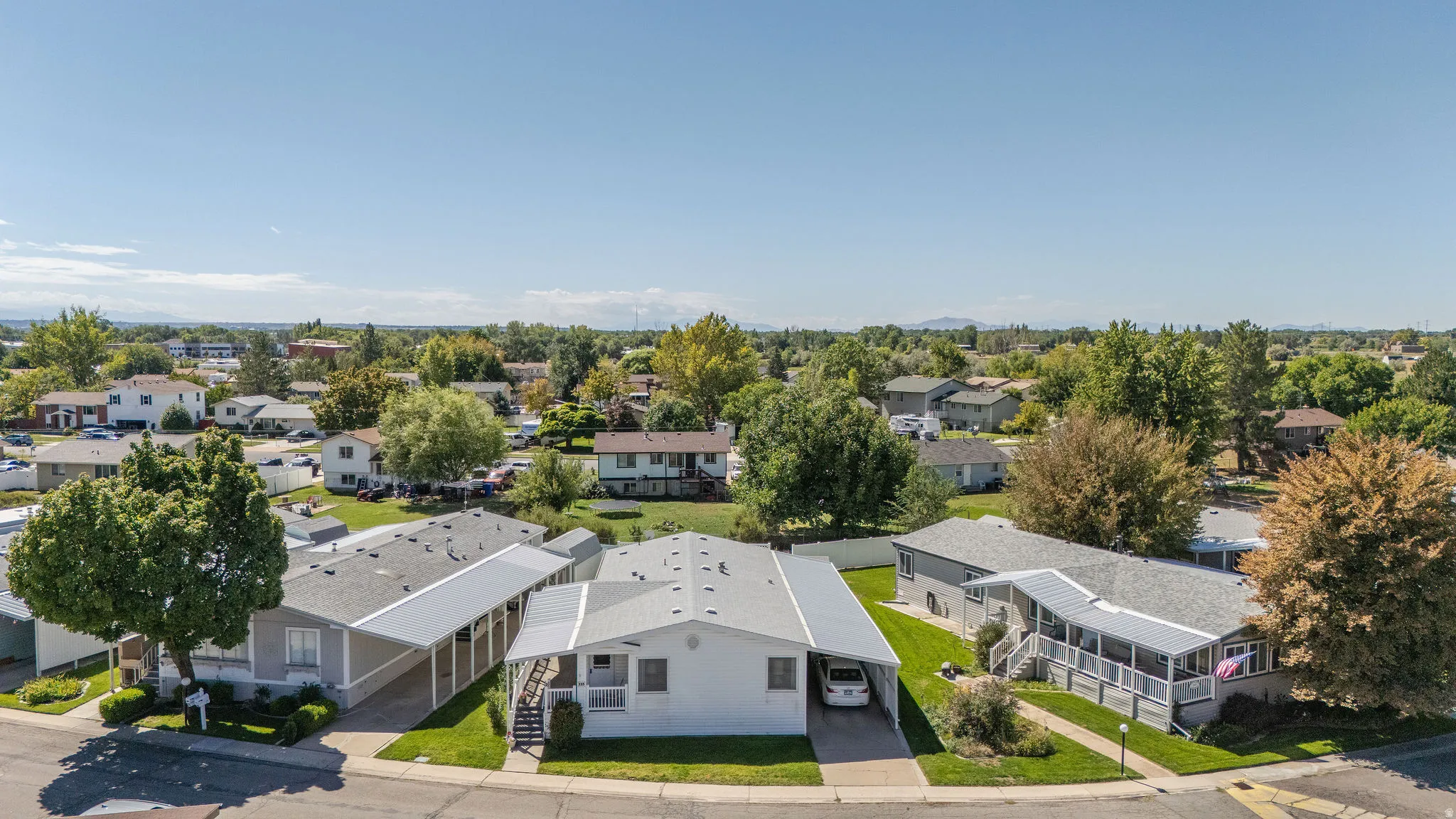 Paved driveway with an attached carport, covered front porch, and a landscaped yard