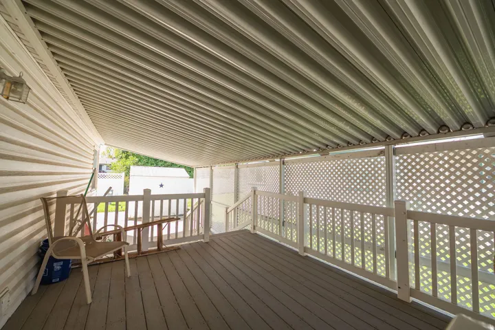 Covered deck featuring finish flooring, white lattice panels, white railing, and exterior wall siding
