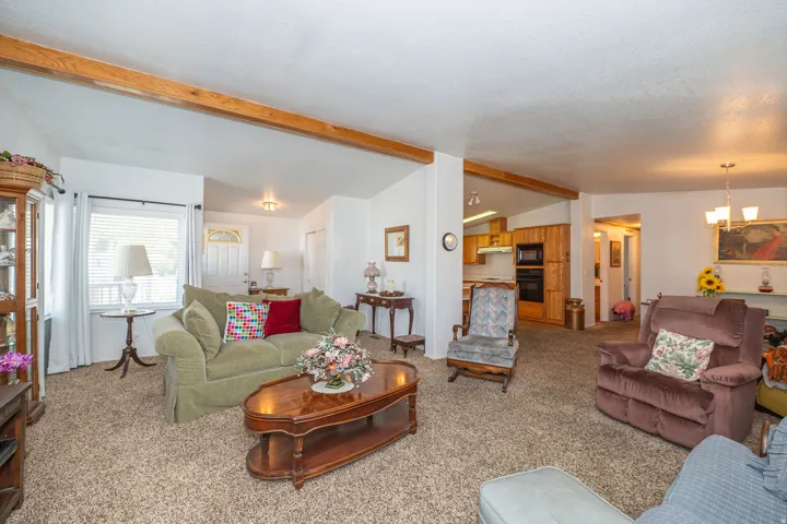 Open-concept living area with exposed beam accents, recessed lighting, and a front entry door with decorative glass