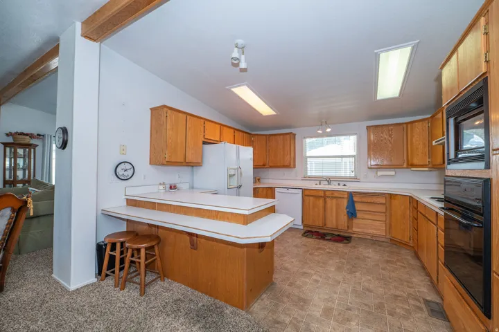 Expansive kitchen featuring light wood cabinetry, white countertops, built-in wall oven and microwave, and track lighting