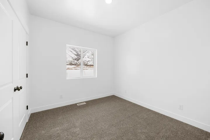 Bright interior with light gray carpeting, white walls, and a window offering natural illumination