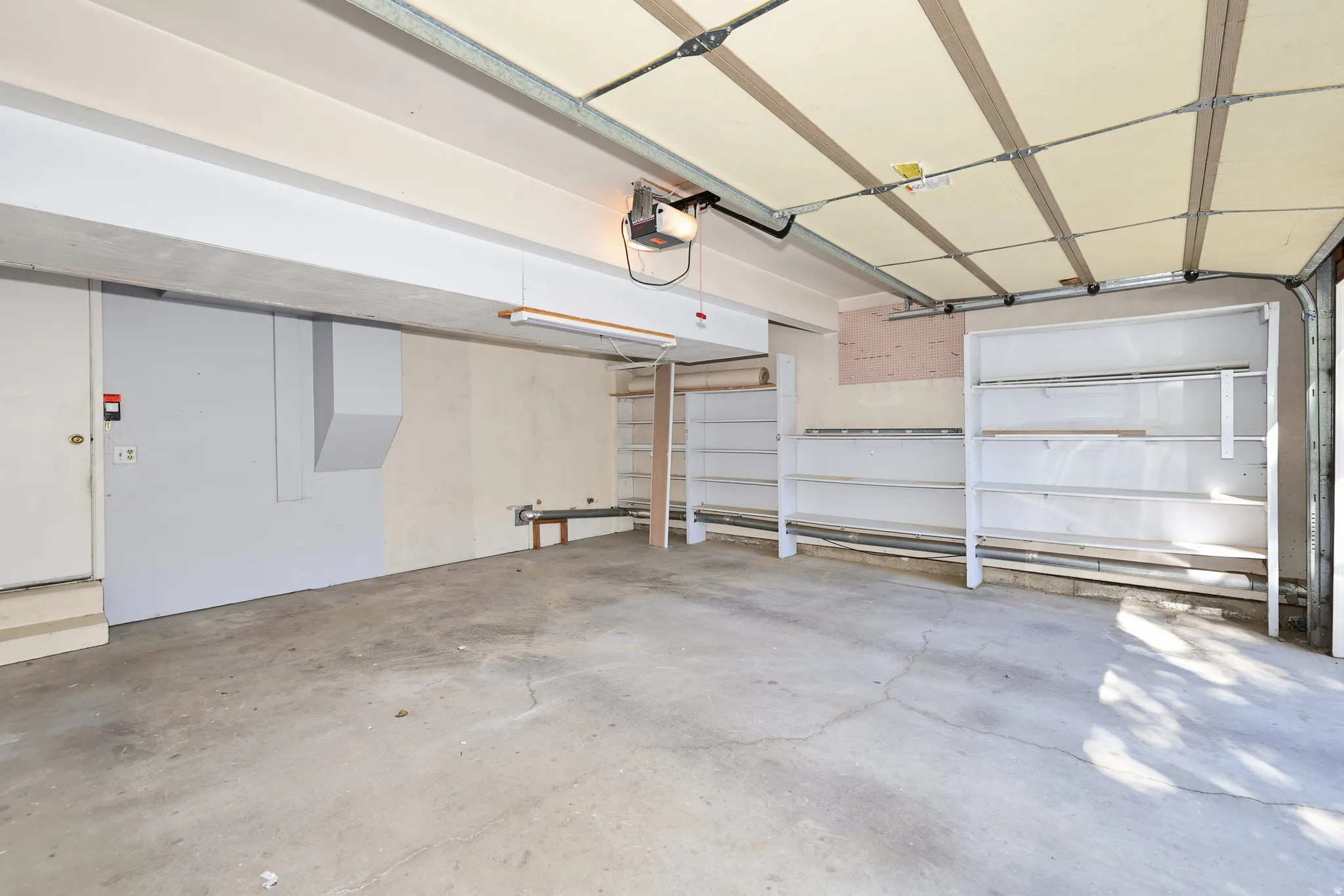 Concrete flooring, built-in shelving, garage door opener, overhead lighting, side access door