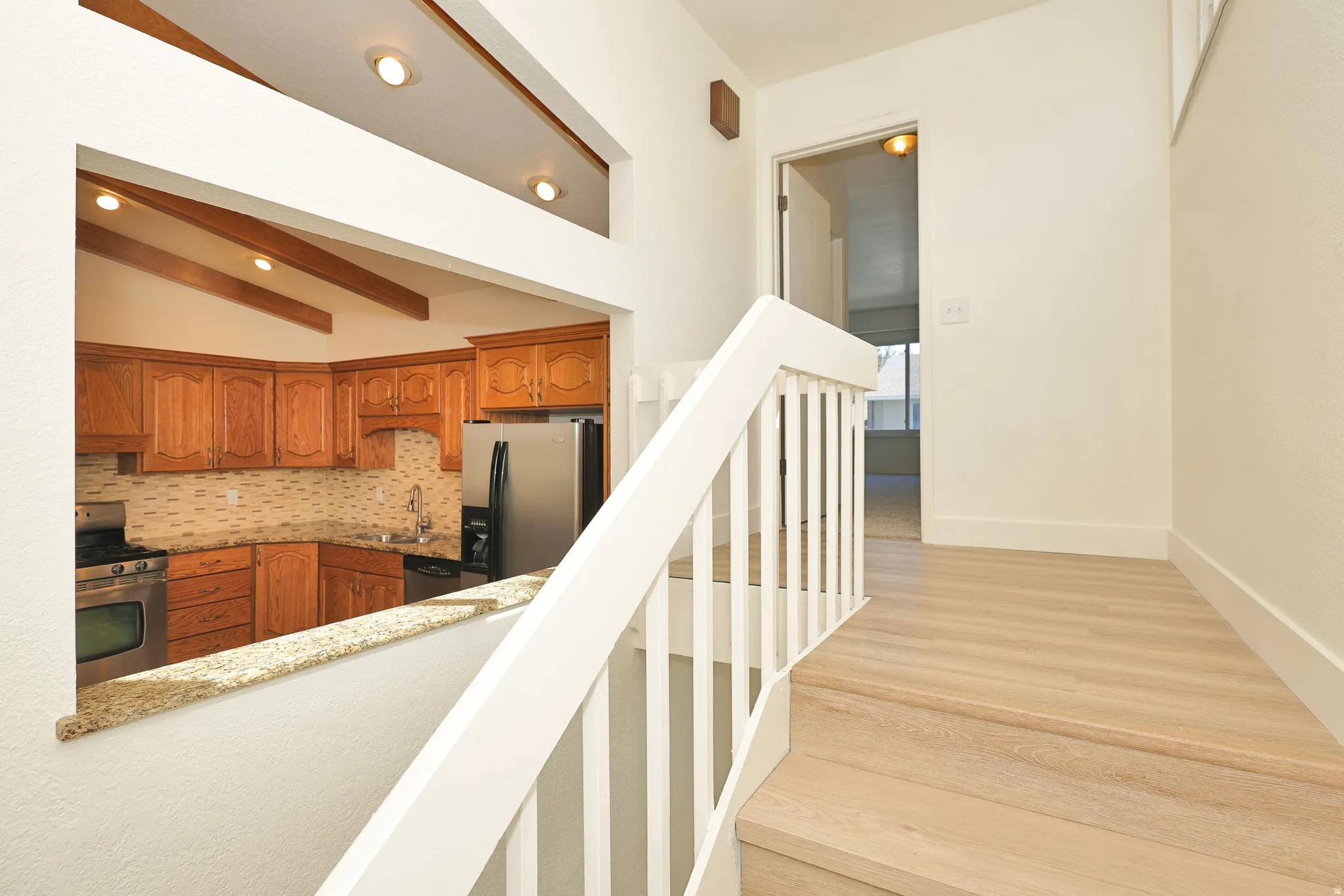 Kitchen with wood cabinetry, stainless steel appliances, and a mosaic tile backsplash