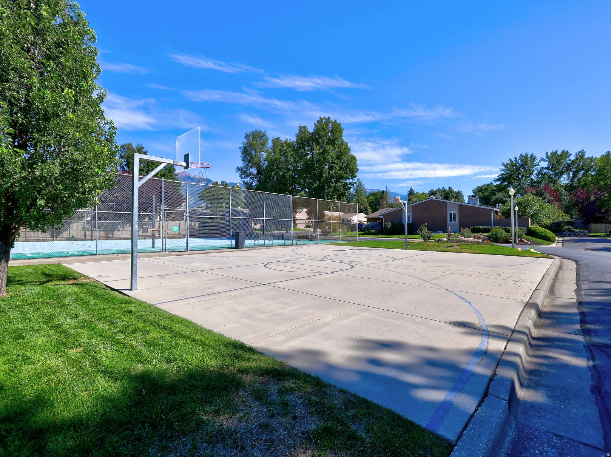 Recreational court featuring a basketball hoop and paved surface