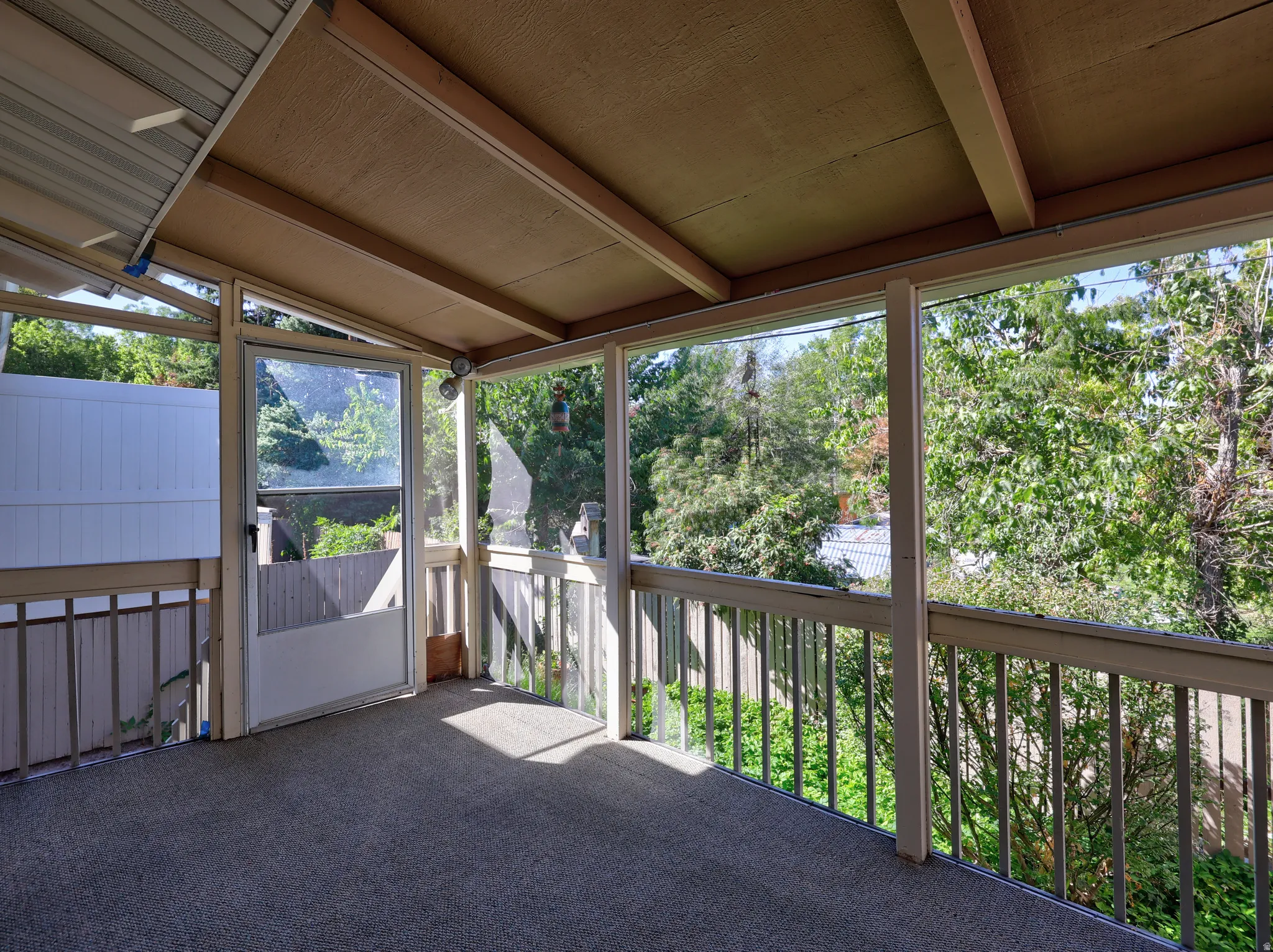 Screened patio with a carpeted floor, wood railings, and a solid overhead covering