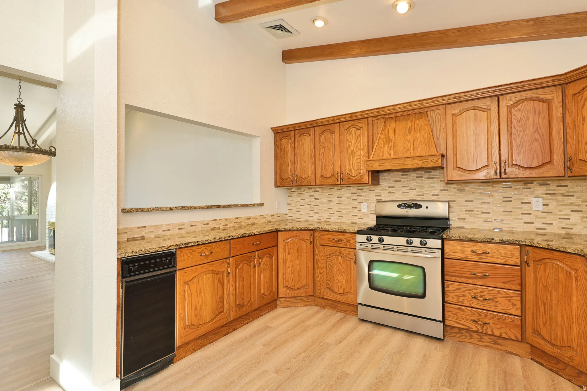 Kitchen featuring wood cabinetry, light-toned countertops, a tile backsplash, stainless steel range, and wood-finish flooring
