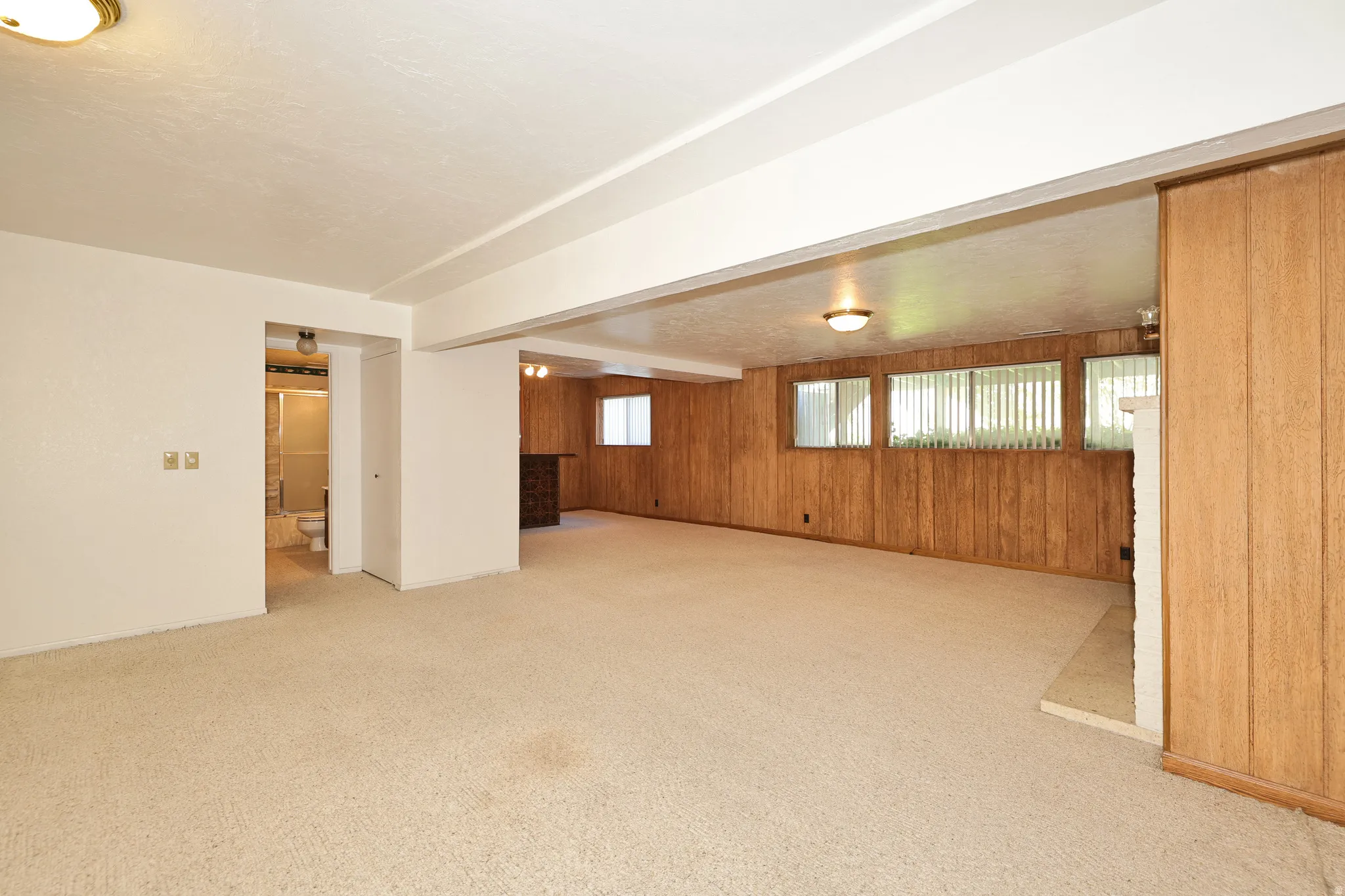Spacious room with carpeted flooring, wood paneling, and a built-in fireplace