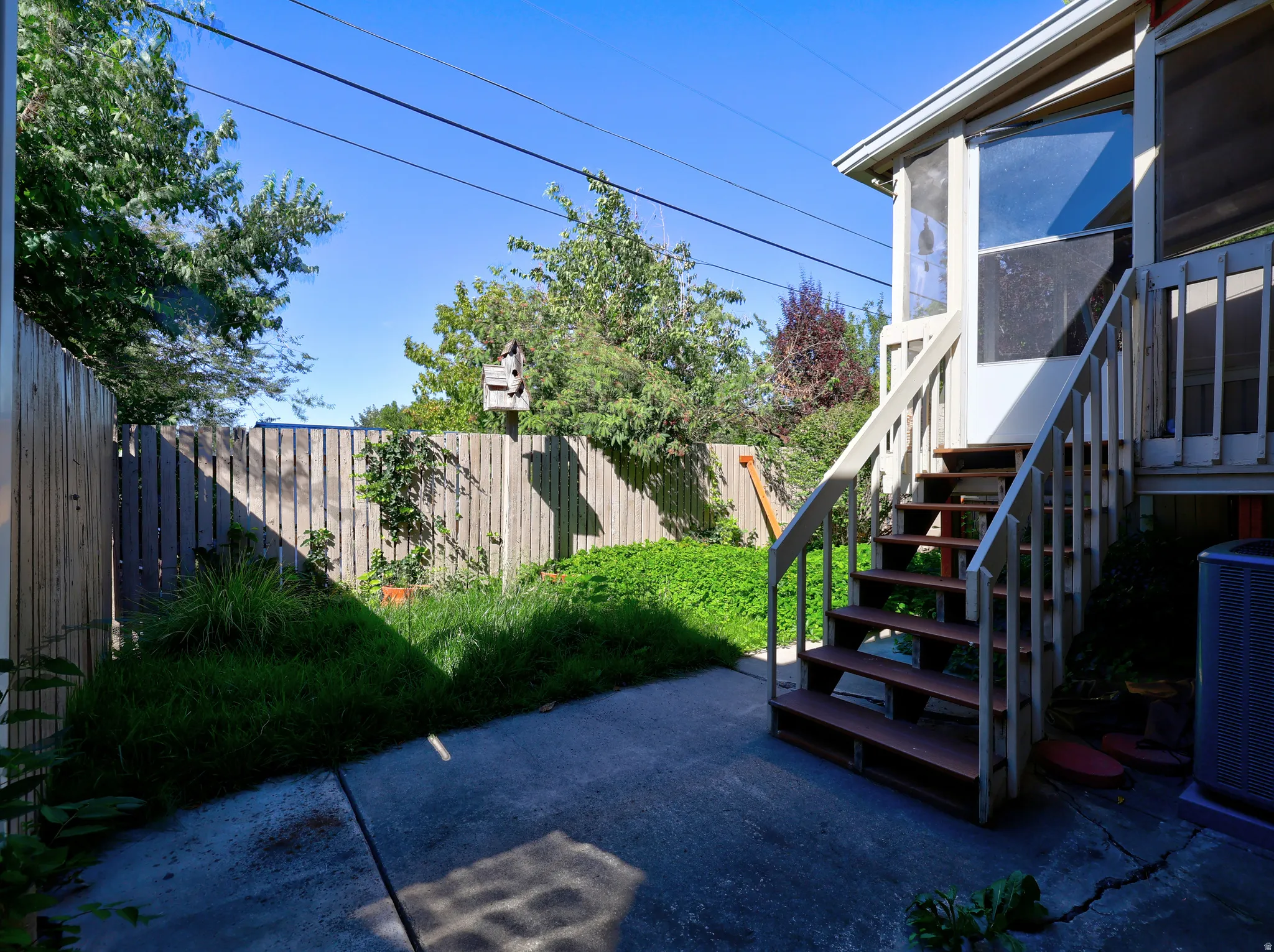 Private backyard area featuring a concrete patio, wooden privacy fencing, and mature greenery
