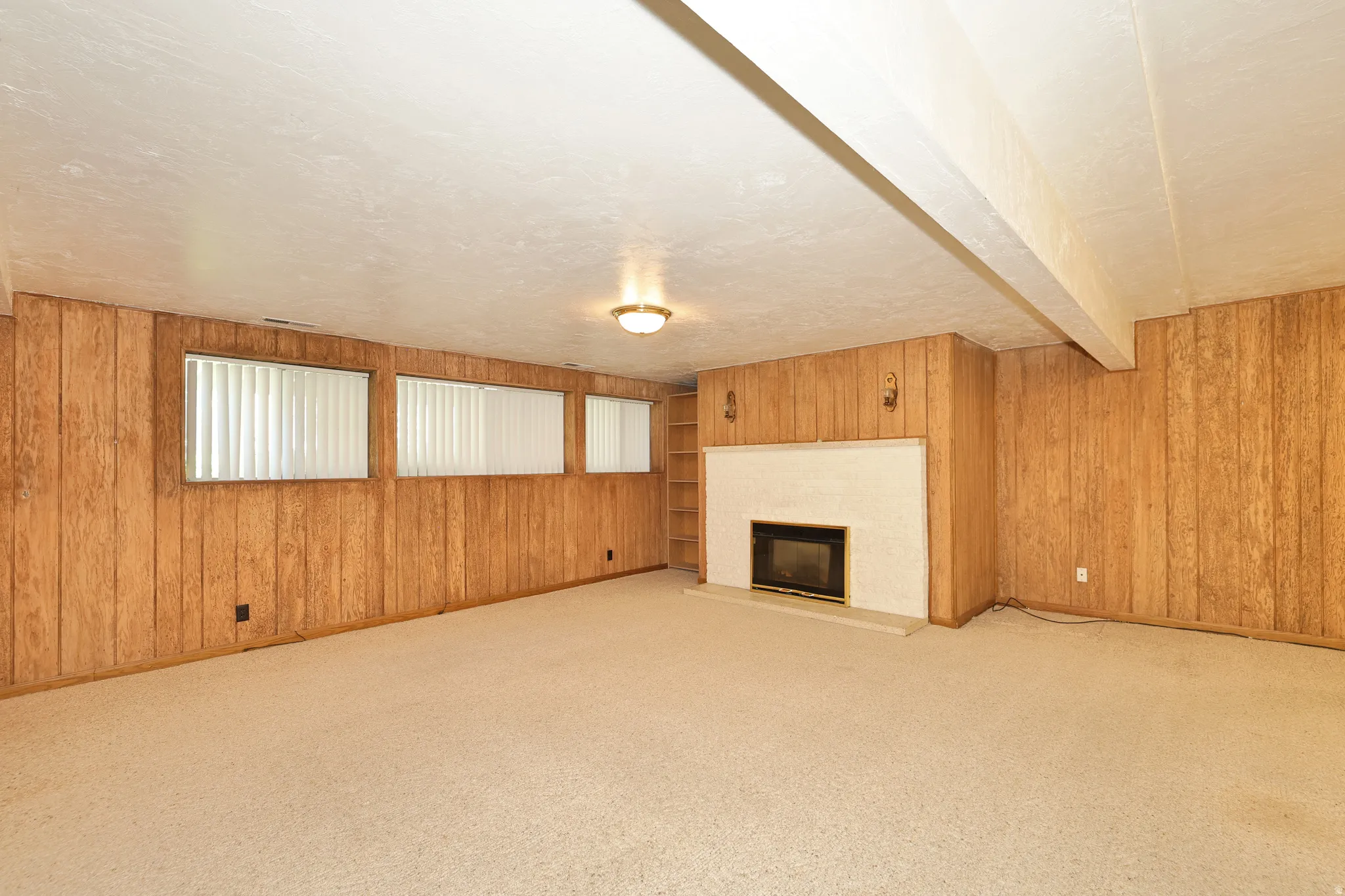 Wood paneling accents a room featuring a white brick fireplace with a black firebox