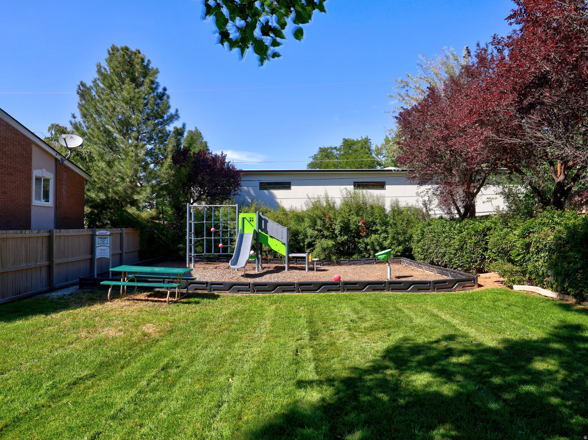 Expansive lawn area with a built-in play structure, retaining walls, and mature landscaping