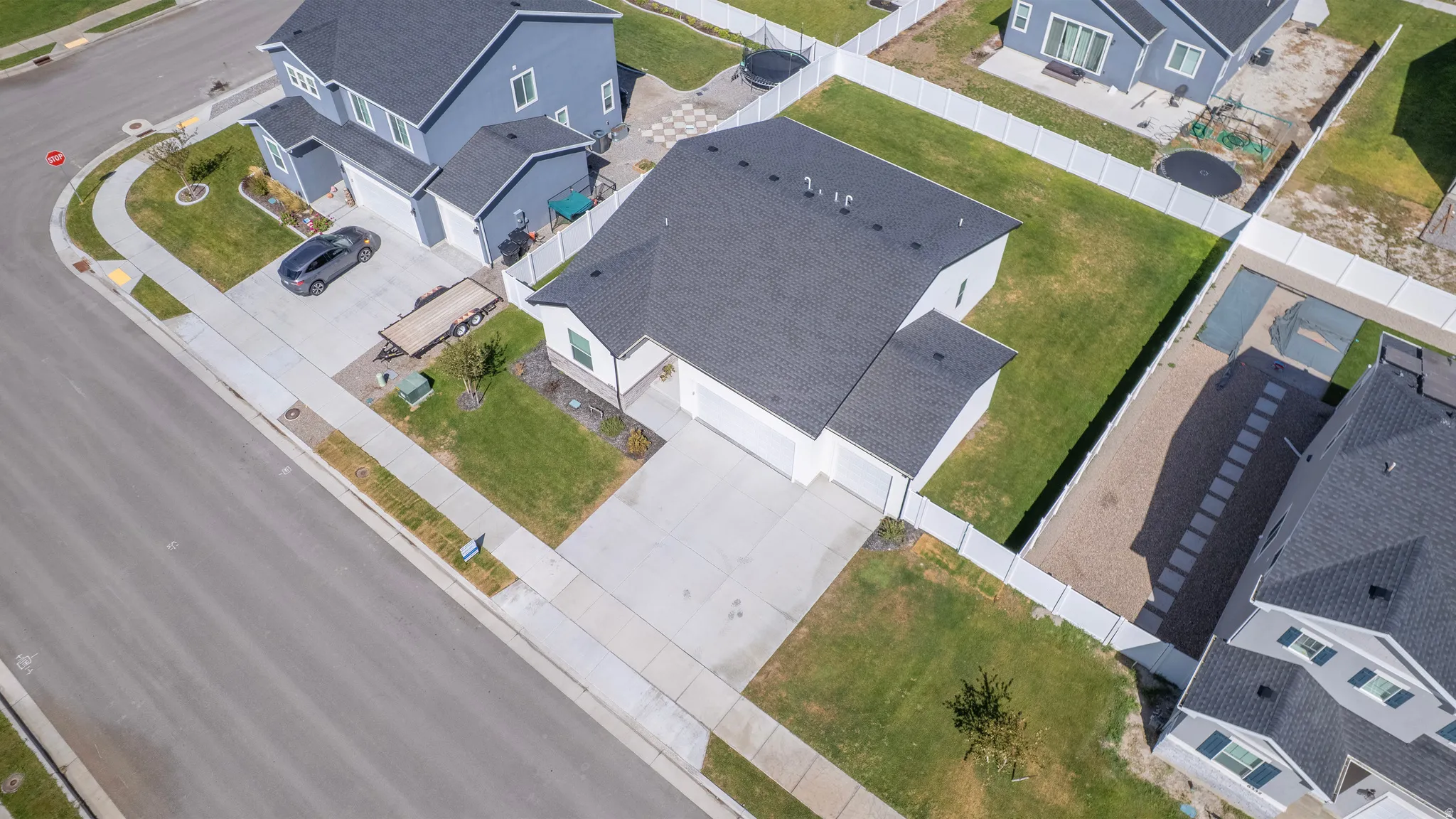 Expansive asphalt shingles on the roof, concrete driveway, and a white fence enclosing the property