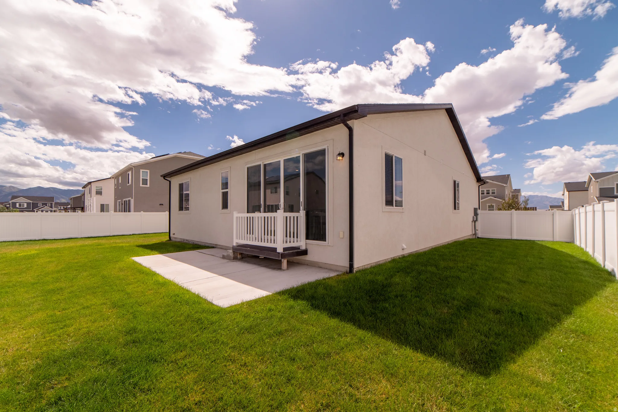 Expansive backyard featuring a manicured lawn, a concrete patio, and a privacy fence
