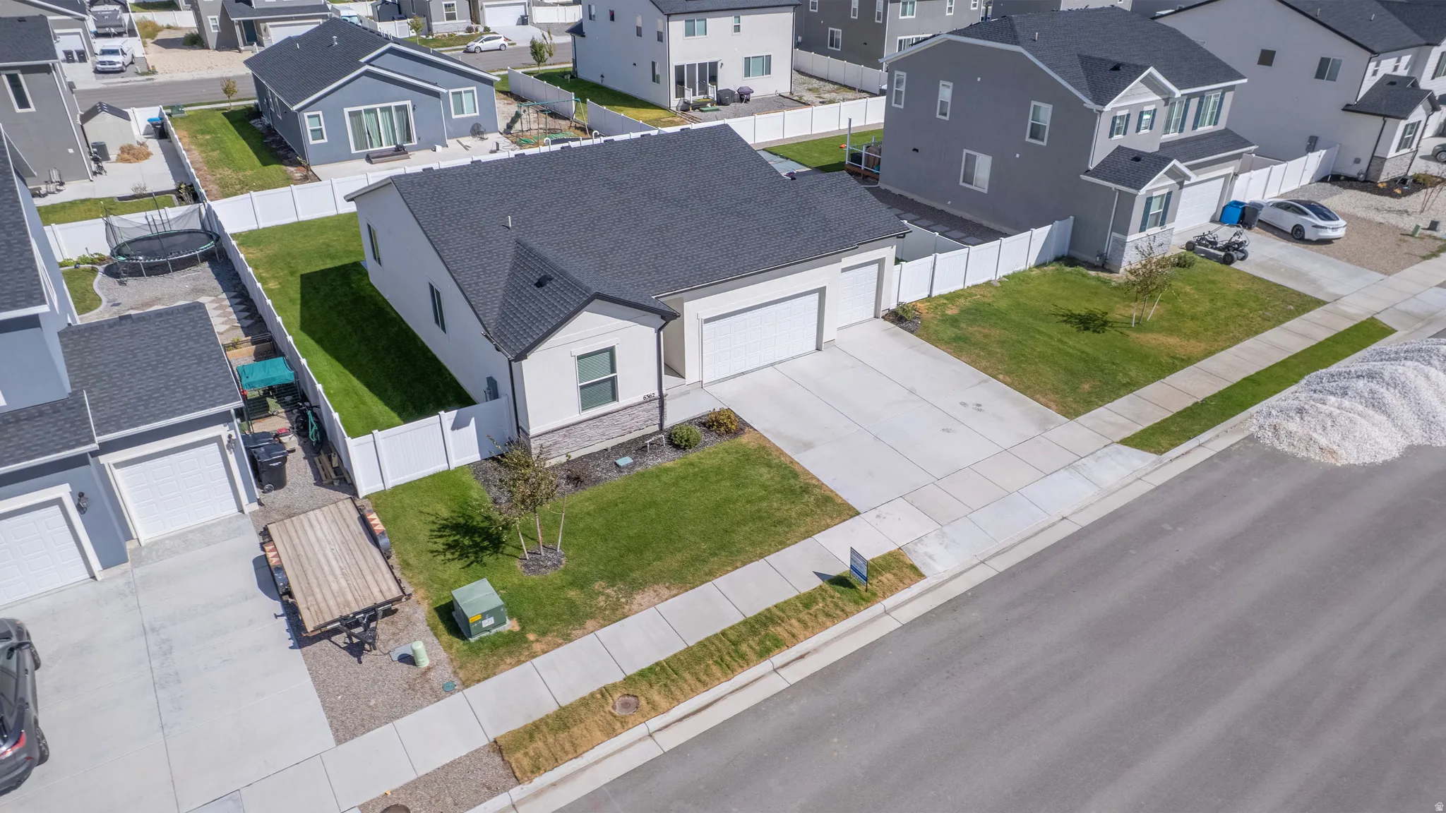 Single-story residence featuring a two-car garage, dark shingle roof, and light-colored siding with a stone-finish accent