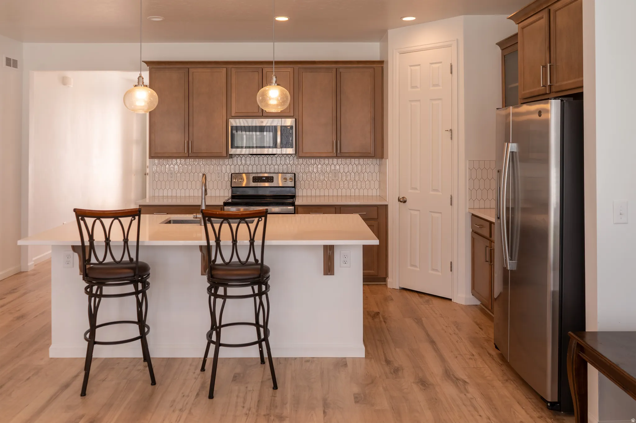 Kitchen featuring wood-finish flooring, a central island with countertop seating, stainless steel appliances, and wood cabinetry