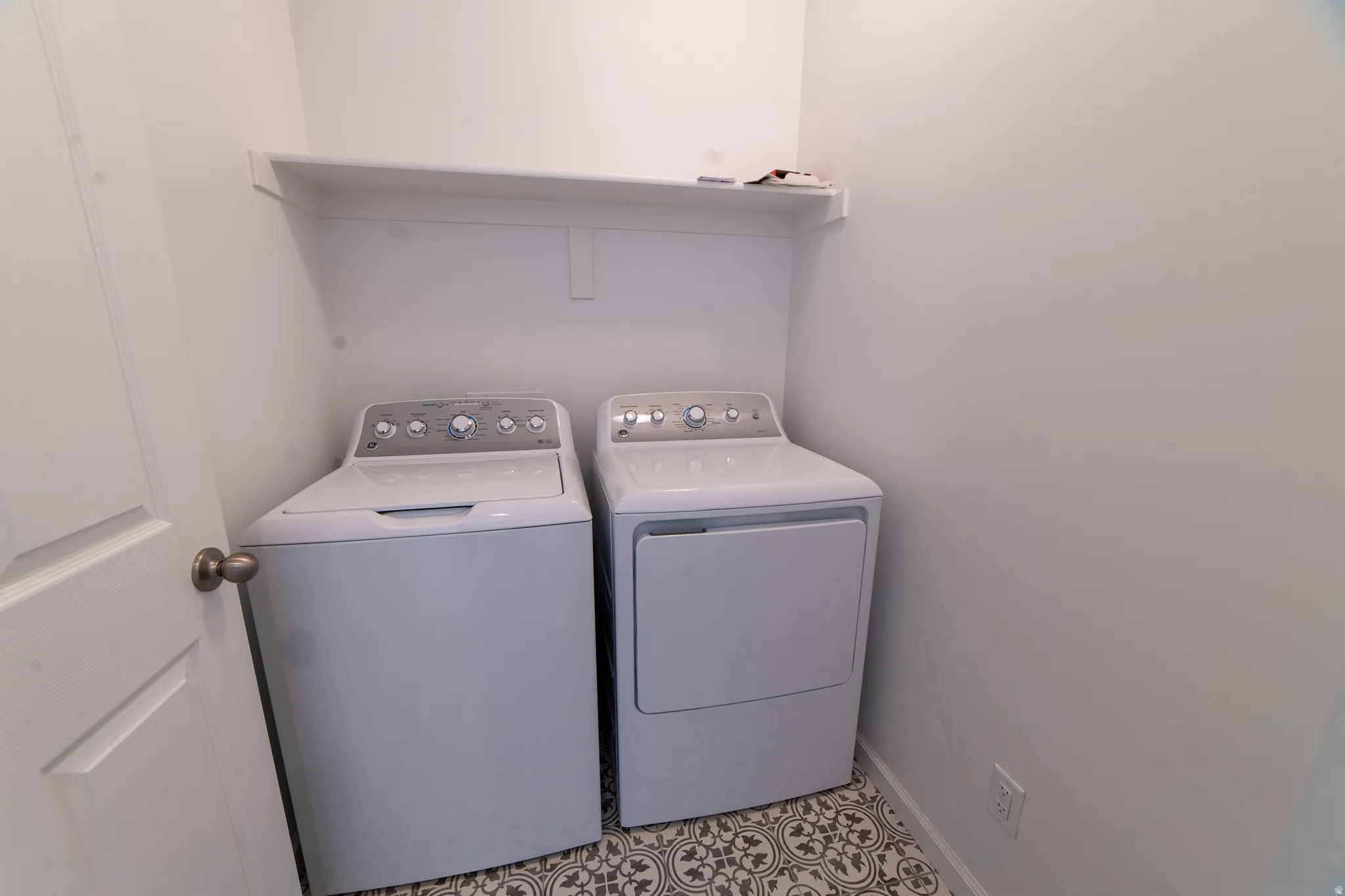 Built-in shelving, patterned floor tile, and a white interior door with bronze hardware