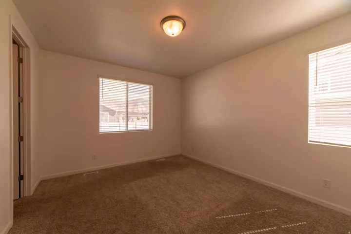 Neutral tone wall finishes, two windows with blinds, flush mount ceiling light, and wall-to-wall carpeting