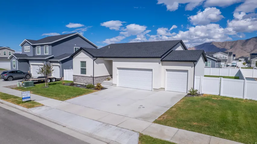 Contemporary exterior with white stucco and stone accents, dual garage doors, and a paved driveway