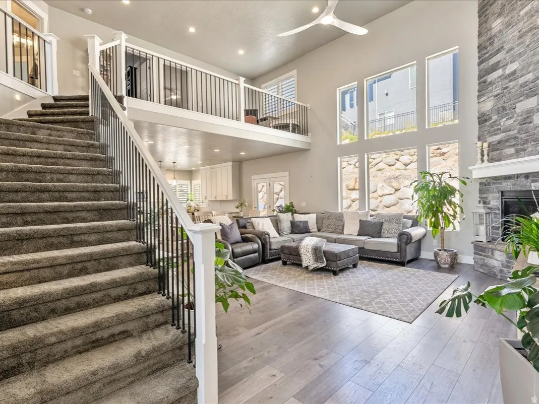 Two-story living area with high ceilings, a stone-clad fireplace, and an open balcony overlooking the space