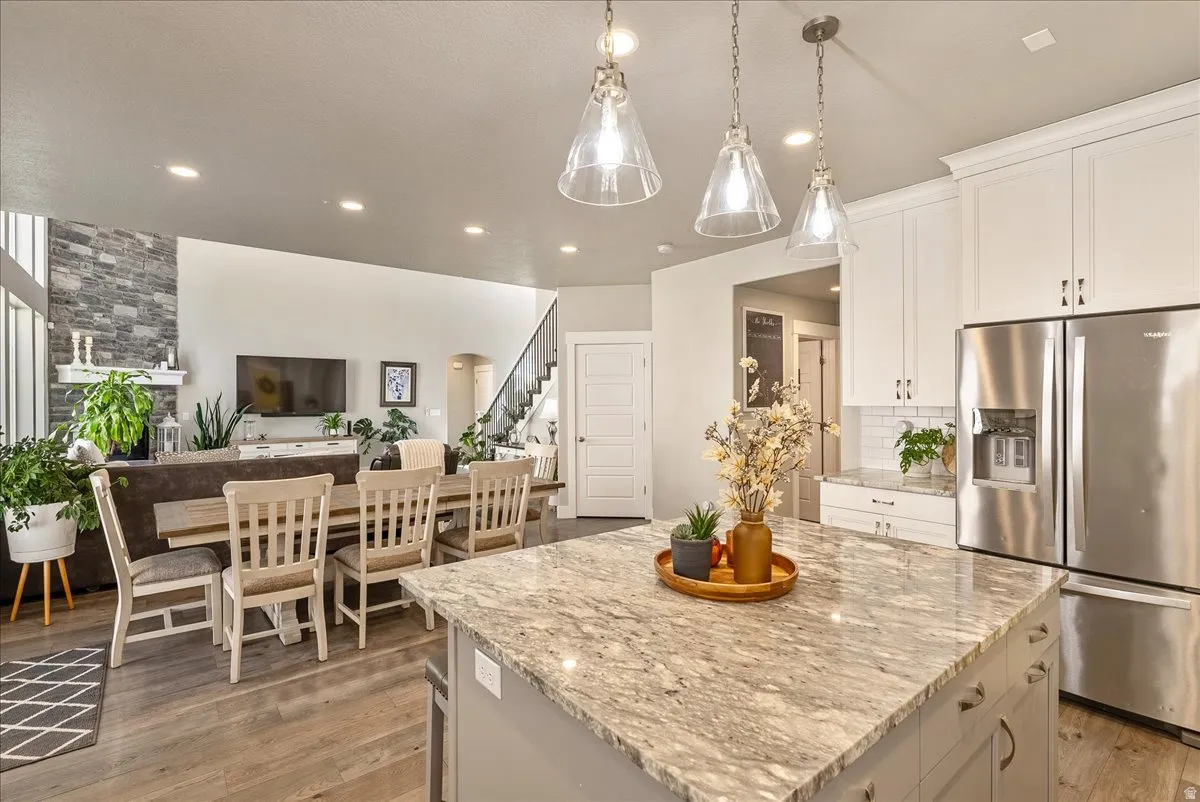 Kitchen island with a light-toned stone countertop and pendant lighting