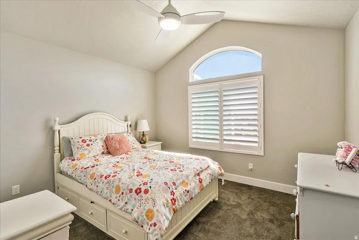 Vaulted ceiling featuring a ceiling fan with integrated lighting, arched transom window, and plantation shutters