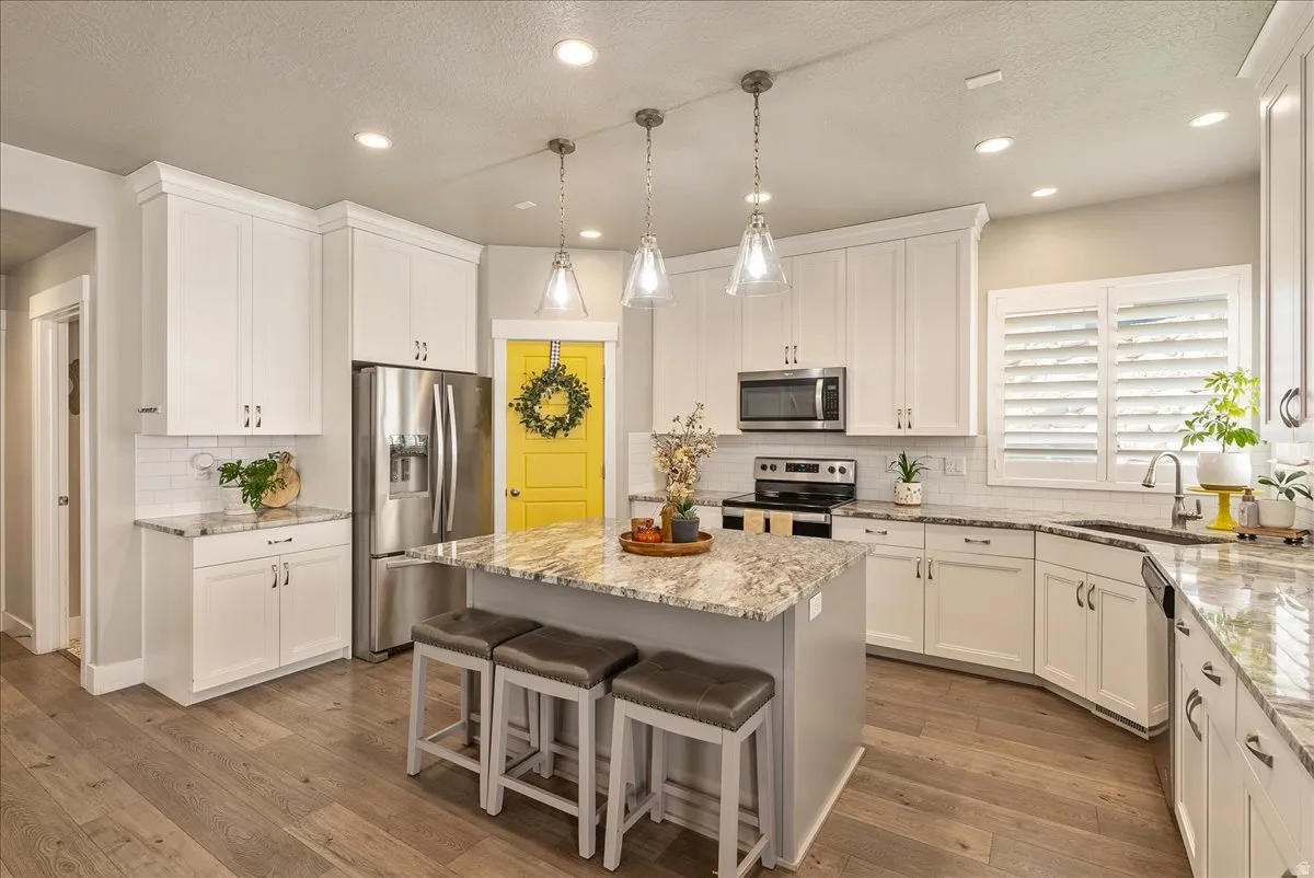 Kitchen featuring white cabinetry, wood-finish flooring, recessed lighting, and an island with pendant lighting