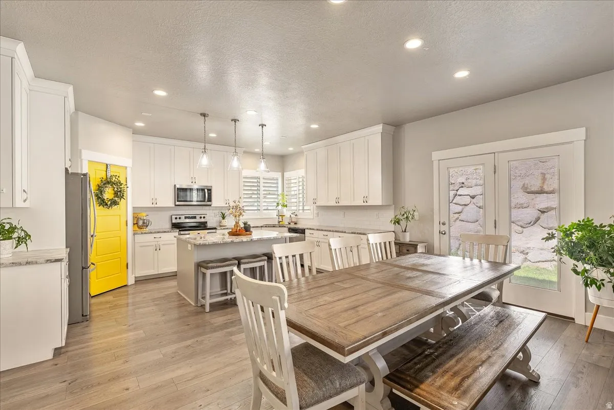 White shaker cabinetry with an island, stone countertops, and wood-finish flooring