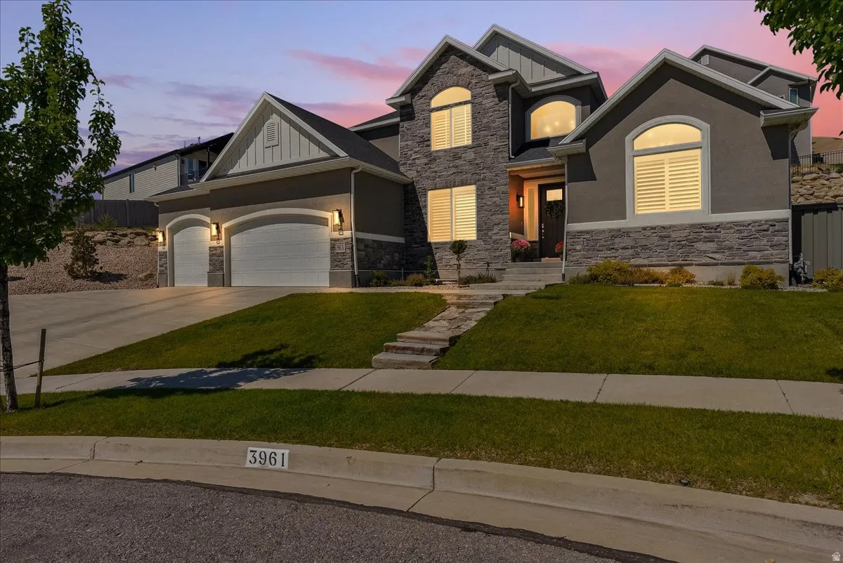 Stone and stucco exterior with multiple gables, arched windows with shutters, and a three-car garage