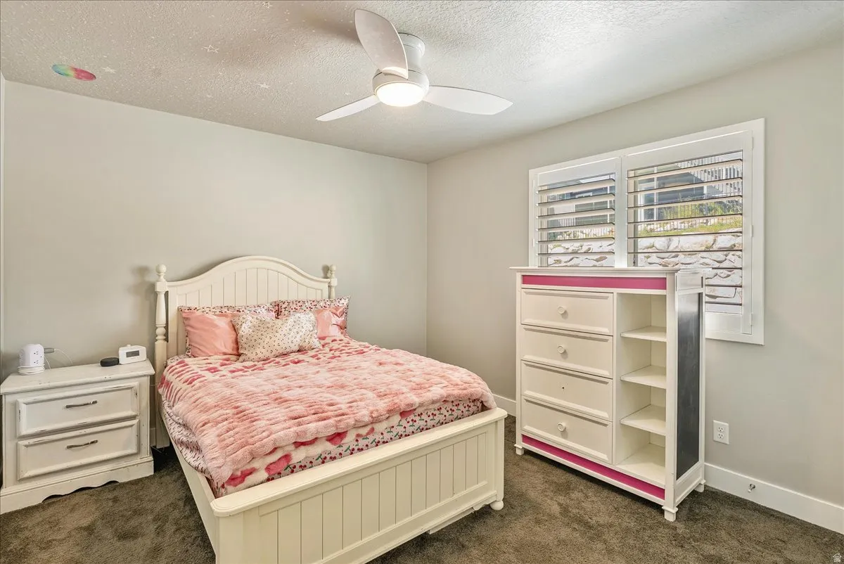 Recessed window with white plantation shutters, white ceiling fan with integrated lighting, and carpeted flooring