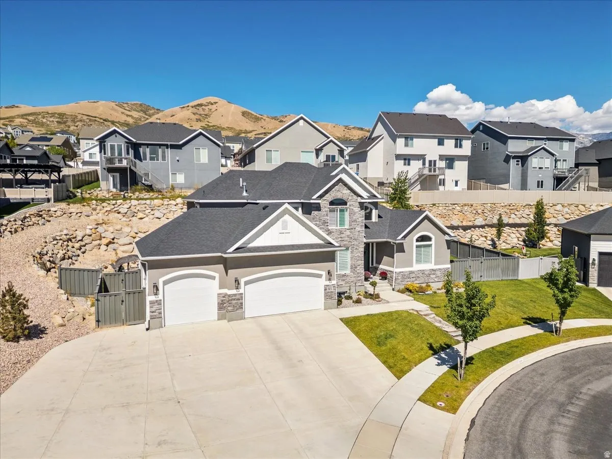 Two-story residence with a three-car garage, stone and stucco exterior, and a paved driveway
