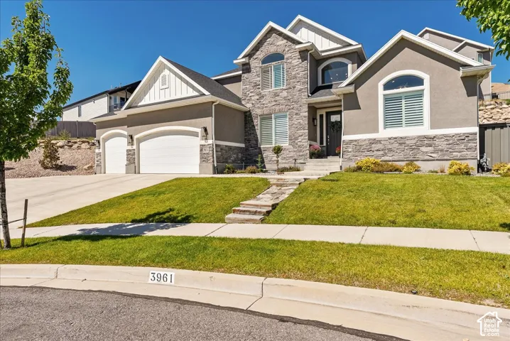 Stucco and stone exterior with arched windows, a covered entry, and an integrated three-car garage