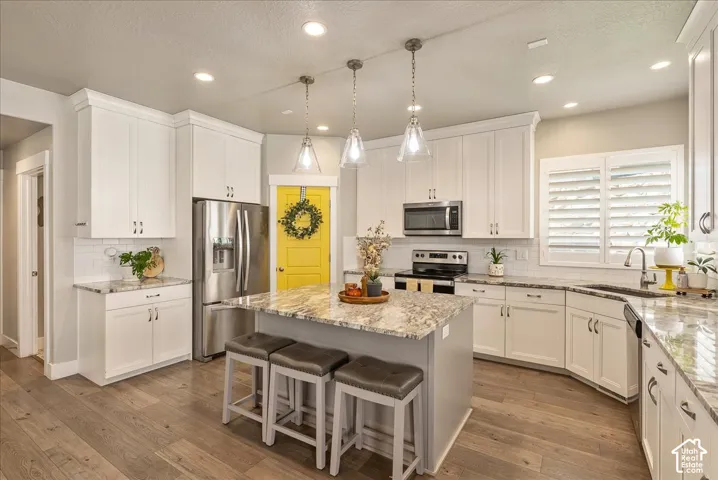 Kitchen featuring white cabinetry, wood-finish flooring, recessed lighting, and an island with pendant lighting