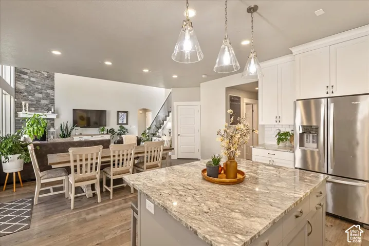 Kitchen island with a light-toned stone countertop and pendant lighting