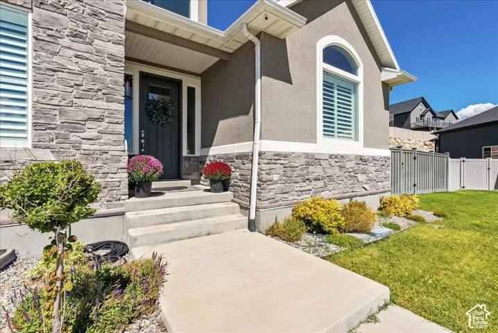 Stone veneer facade, stucco exterior, arched window, concrete walkway, and landscaped garden beds