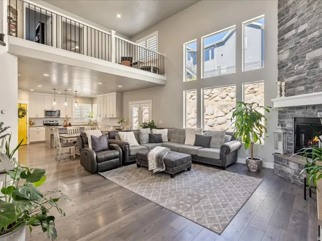 Two-story great room with a stone fireplace, wood-finish flooring, and a second-story interior balcony