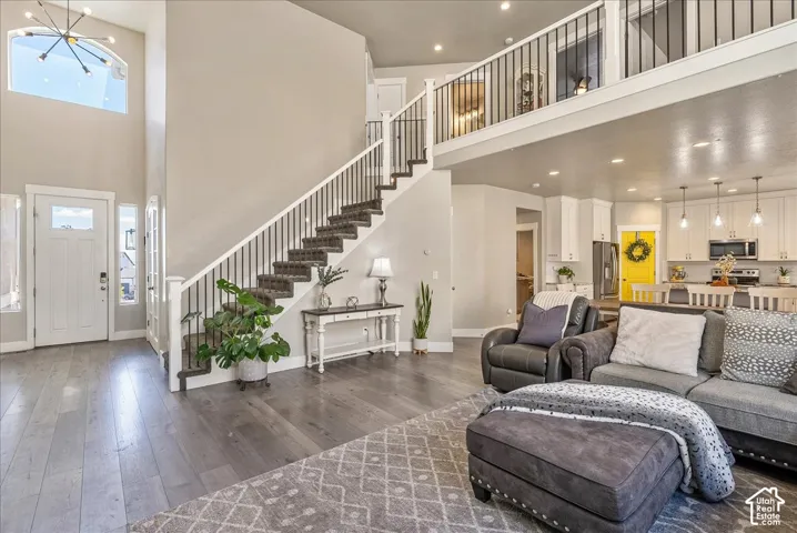 Vaulted entry with an arched window and chandelier, wood-finish flooring, and a grand staircase with wrought iron balusters