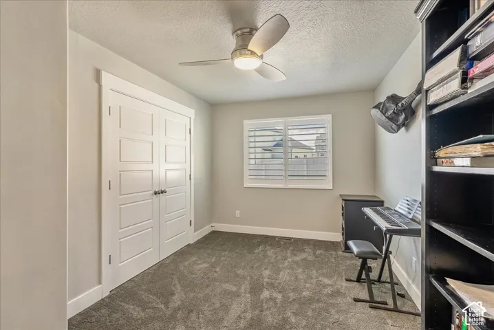 Carpeted bedroom with a ceiling fan, window with white louvered shutters