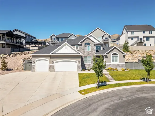 Three-car garage with arched doors, gray stucco and stone exterior, white trim accents, arched window, and concrete driveway
