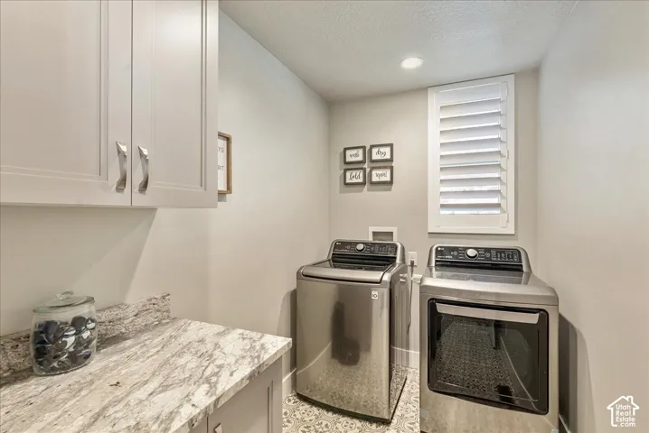 Upper cabinetry with brushed nickel hardware, granite-style countertop, window with plantation shutters, recessed lighting, and patterned floor tile