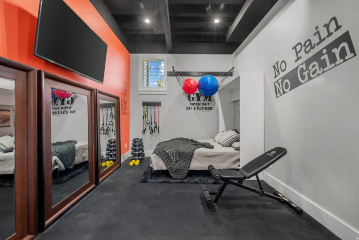 Dedicated fitness area featuring rubberized flooring, built-in recessed lighting, and a window with plantation shutters