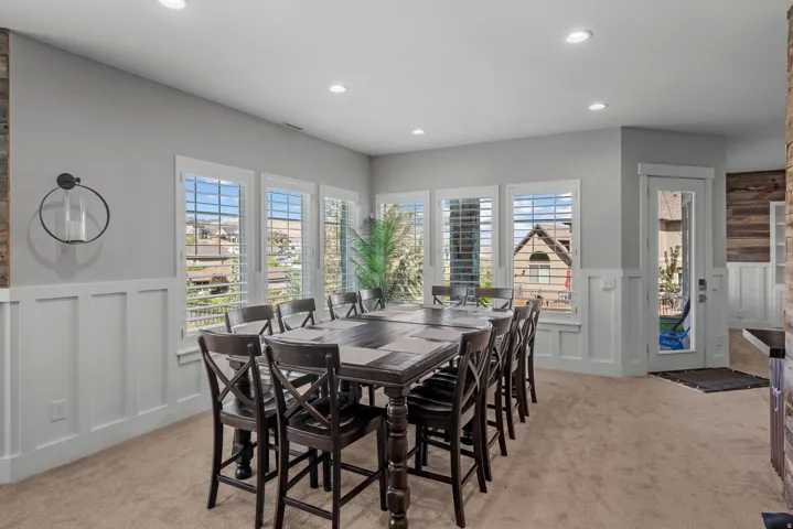 Recessed lighting, large windows with plantation shutters, wainscoting, and wood-finish accent wall