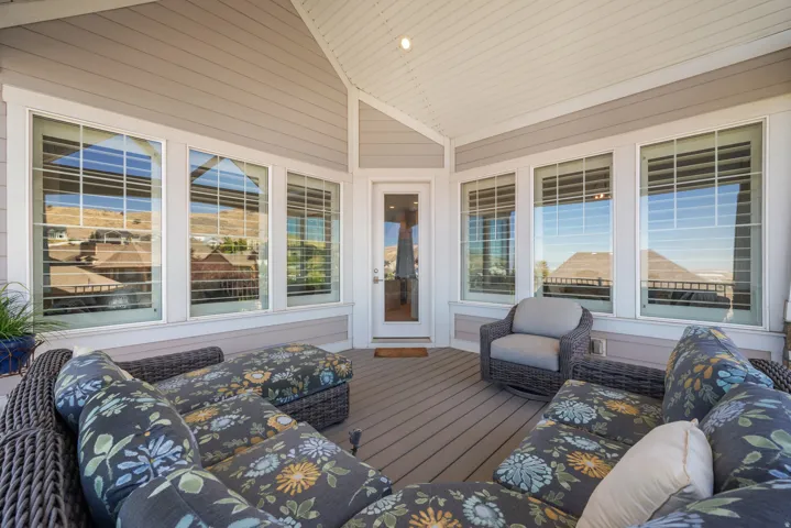 Covered deck featuring a composite deck floor, multiple large windows, and a glass-paneled exterior door