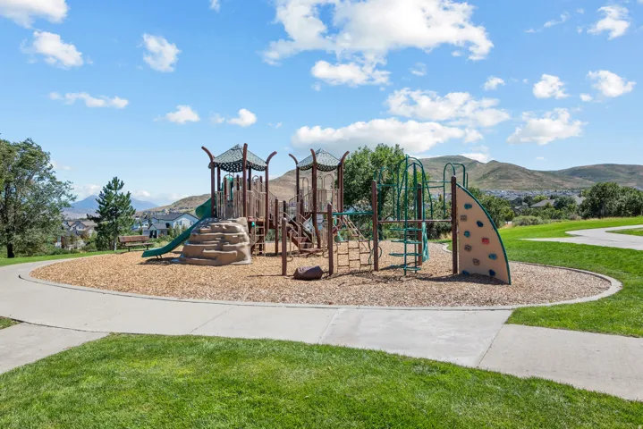 Community playground with multiple play structures, a rock-climbing wall, slide, and wood chip surfacing