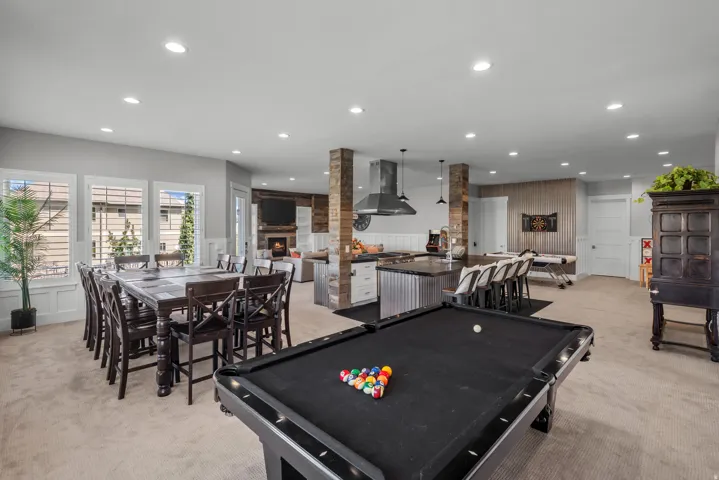Open-concept recreation space featuring a billiards table, dining area, and a kitchen island with seating