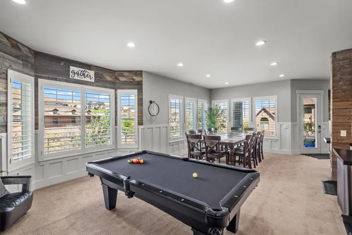 Recessed lighting, bay windows with plantation shutters, wainscoting, wood-finish accent walls, and an exterior door